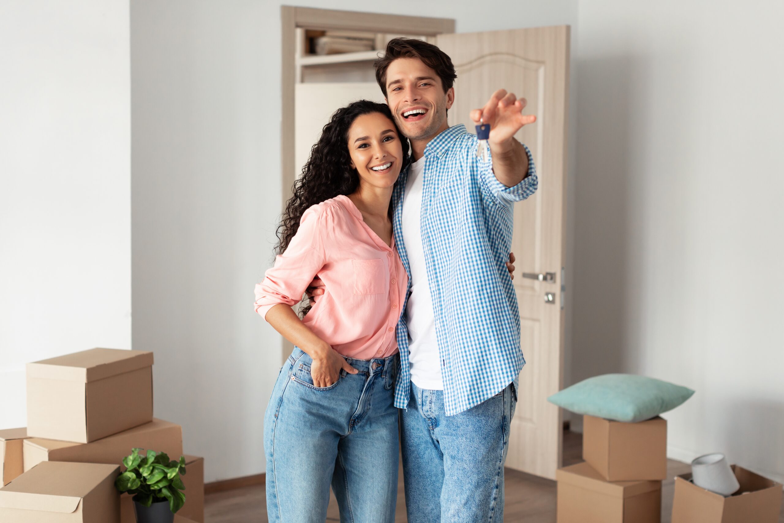 Young Couple Holding Showing Key Standing in New House