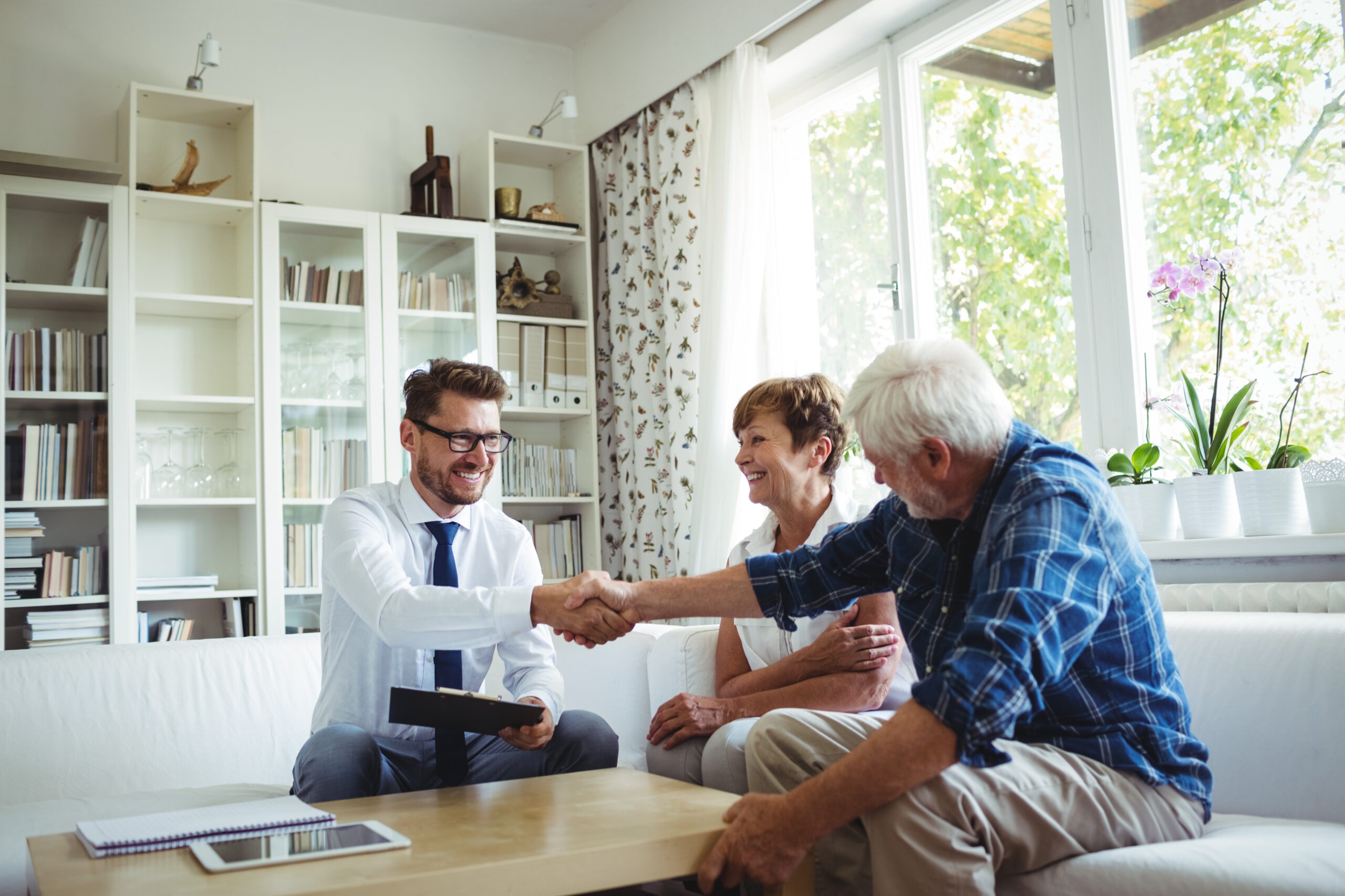 Financial Advisor Shaking Hands with Senior Man in Living Room